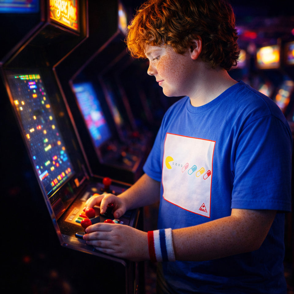 Young boy playing an arcade game in a darkly lit arcade.
