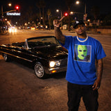 Man in blue t-shirt with graphic design standing next to a classic black convertible car on a city street at night.